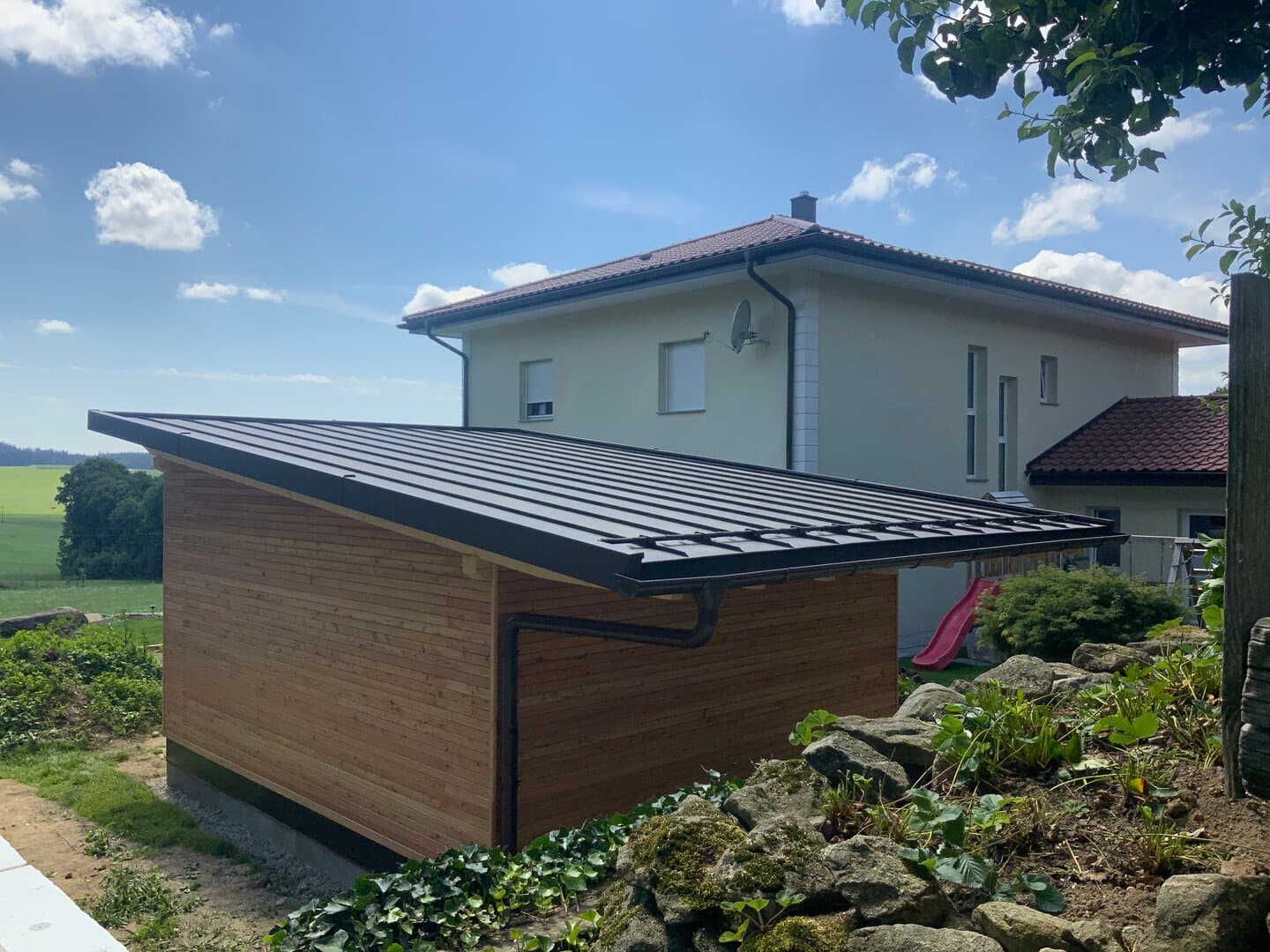 Carport mit schwarzem Stehfalzdach und Holzfassade