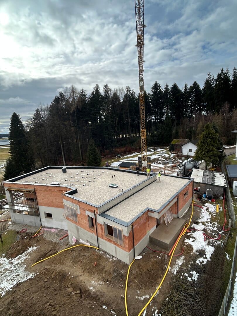 Flachdach-Neubau mit Baukran aus der Vogelperspektive