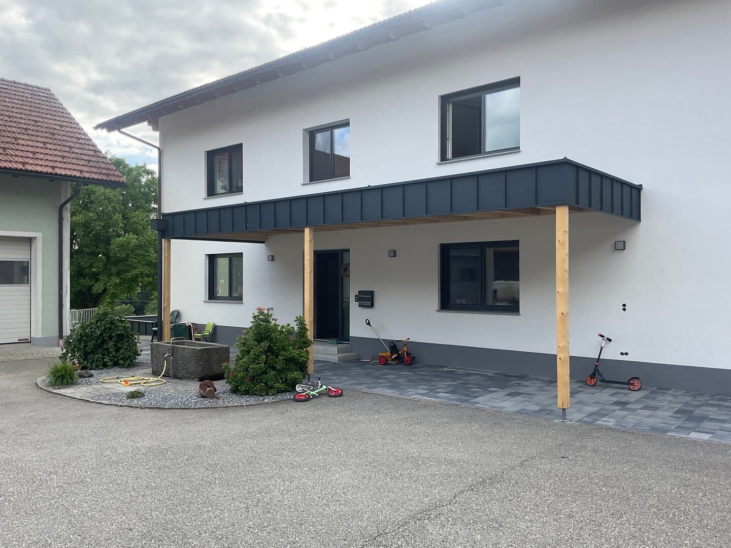 Flaches Vordach mit dunkler Blechverkleidung