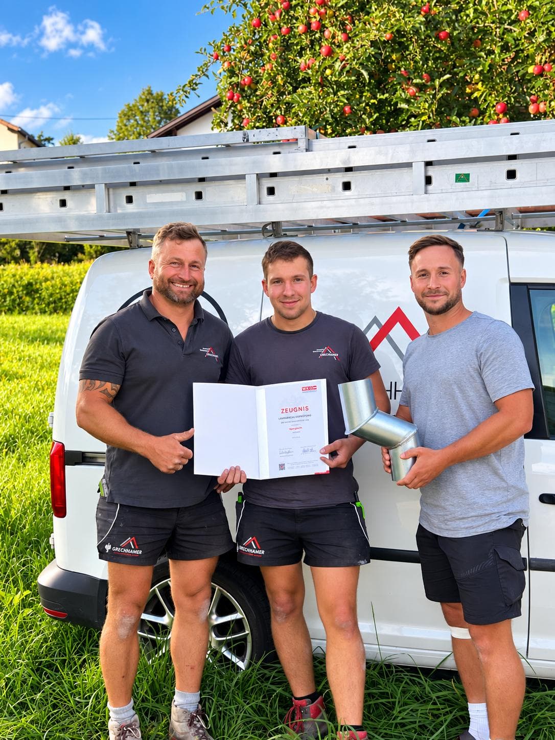 Bastian Friedl mit seinem Lehrabschluss-Zeugnis, gemeinsam mit Andreas Grechhamer und David Ruhmannseder vor dem Firmenbus